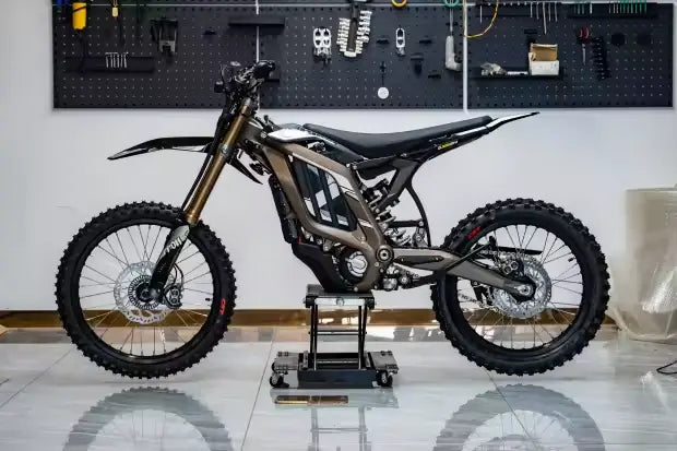 2026 Sur-Ron Light Bee LBX2 electric dirt bike full side profile in titanium grey on workshop lift stand.