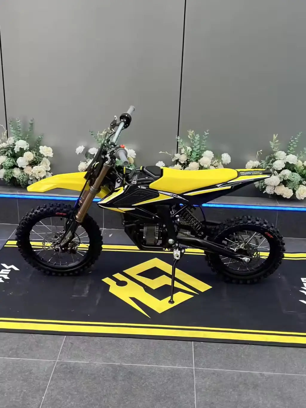 2026 Sur-Ron Hyper Bee electric dirt bike in yellow black colorway side profile view on display mat.