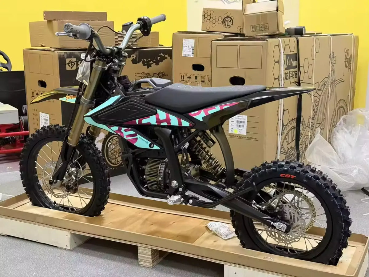 2026 Sur-Ron Hyper Bee electric dirt bike with cyan pink graphics on factory shipping crate profile view.