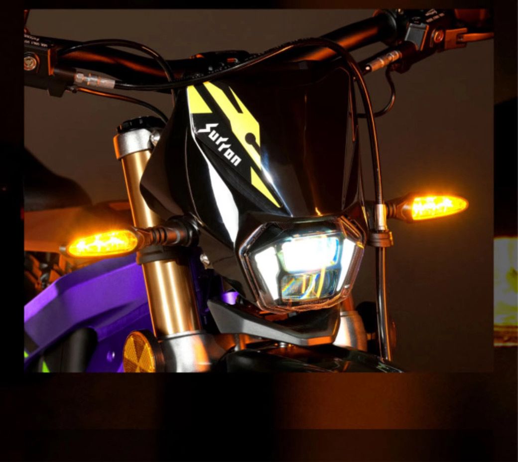 Close-up of 2026 Sur-Ron Light Bee X 3C front LED headlight array and dual amber LED turn signal indicators mounted on gold USD suspension forks.