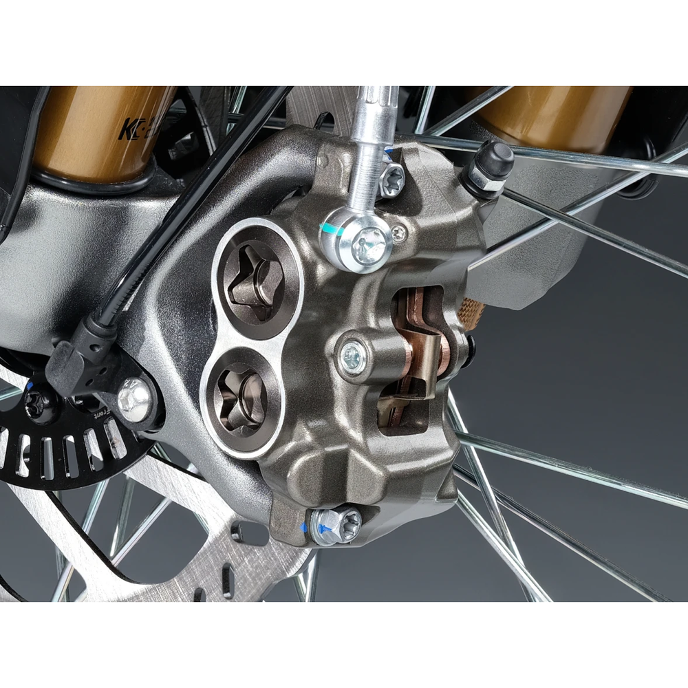Close-up view of 2026 Sur-Ron LBX2 high-performance four-piston hydraulic brake caliper, brake pad assembly, and ventilated disc rotor.