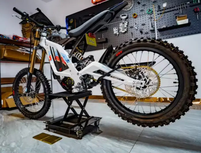 2026 Sur-Ron Light Bee X rear 3/4 view showing CST knobby tire, rear sprocket, and hydraulic disk brake.